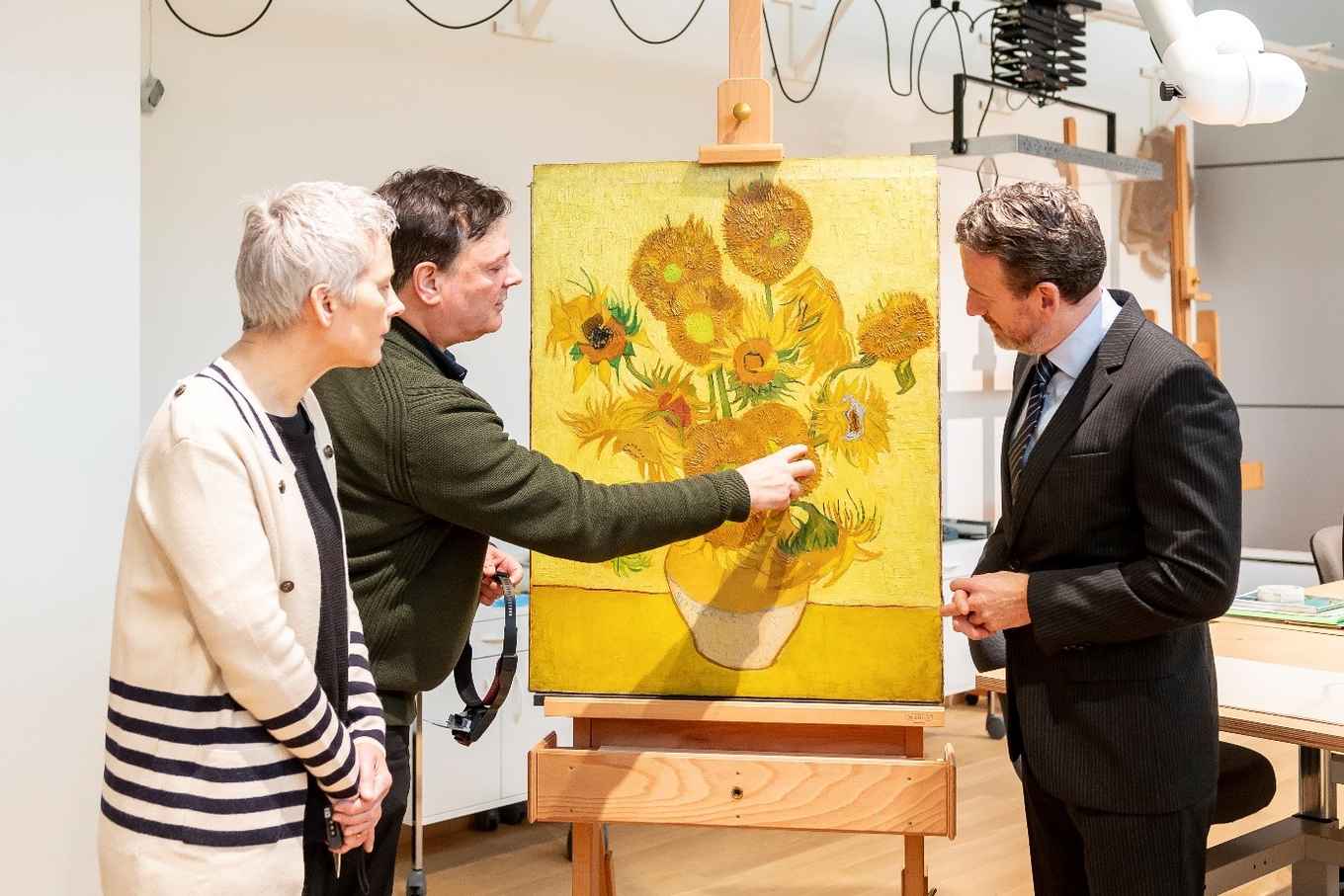 Ella Hendriks (links) met directeur van het Van Gogh Museum Axel Rüger (rechts) en restaurator René Boitelle in het restauratieatelier bij Zonnebloemen (foto: Van Gogh Museum)